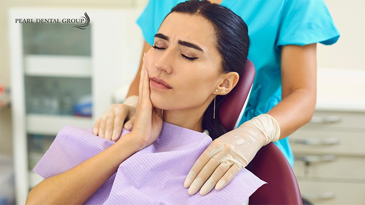 a woman holds her cheek because of severe wisdom tooth pain